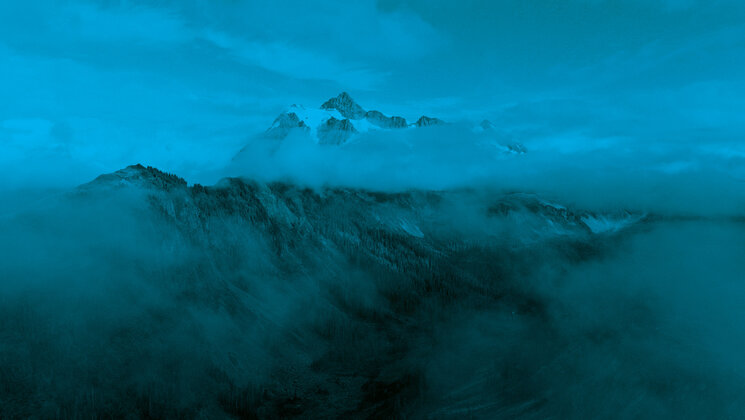 An areal photo of a mountain, with a blue filter.